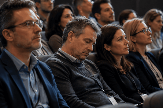 Man struggling to stay awake during a seminar while others listen attentively